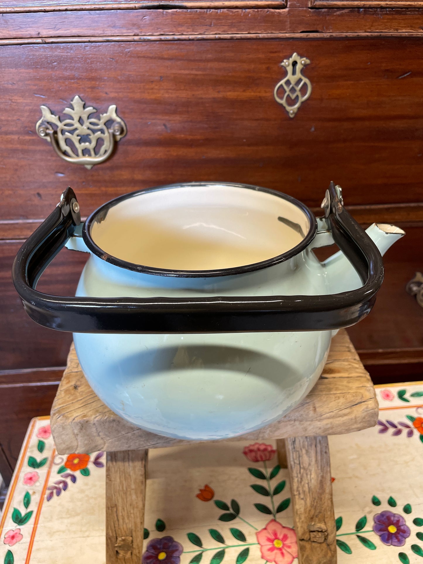 Pale blue enamel kettle with black handle and rim.