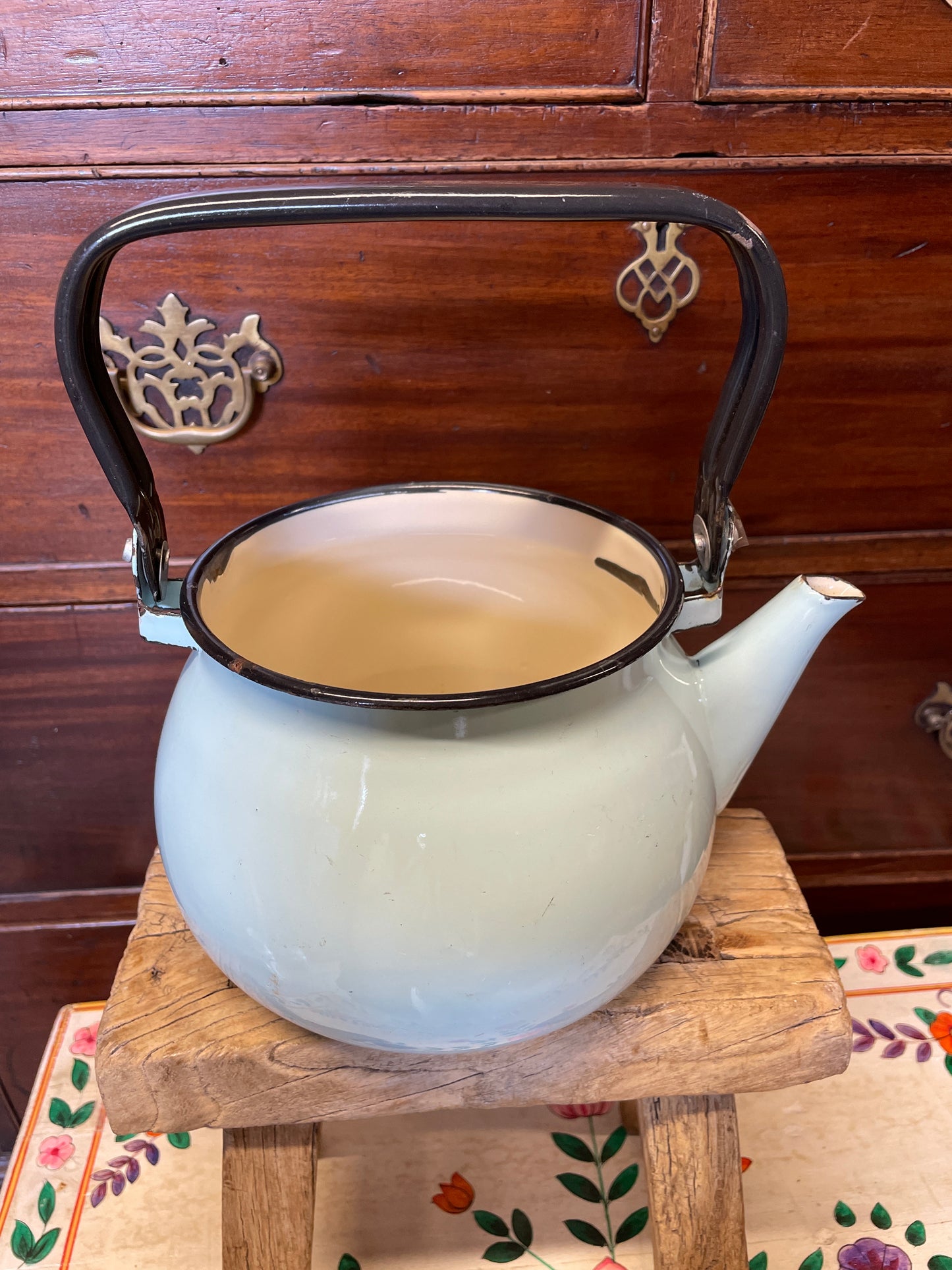 Pale blue enamel kettle with black handle and rim.