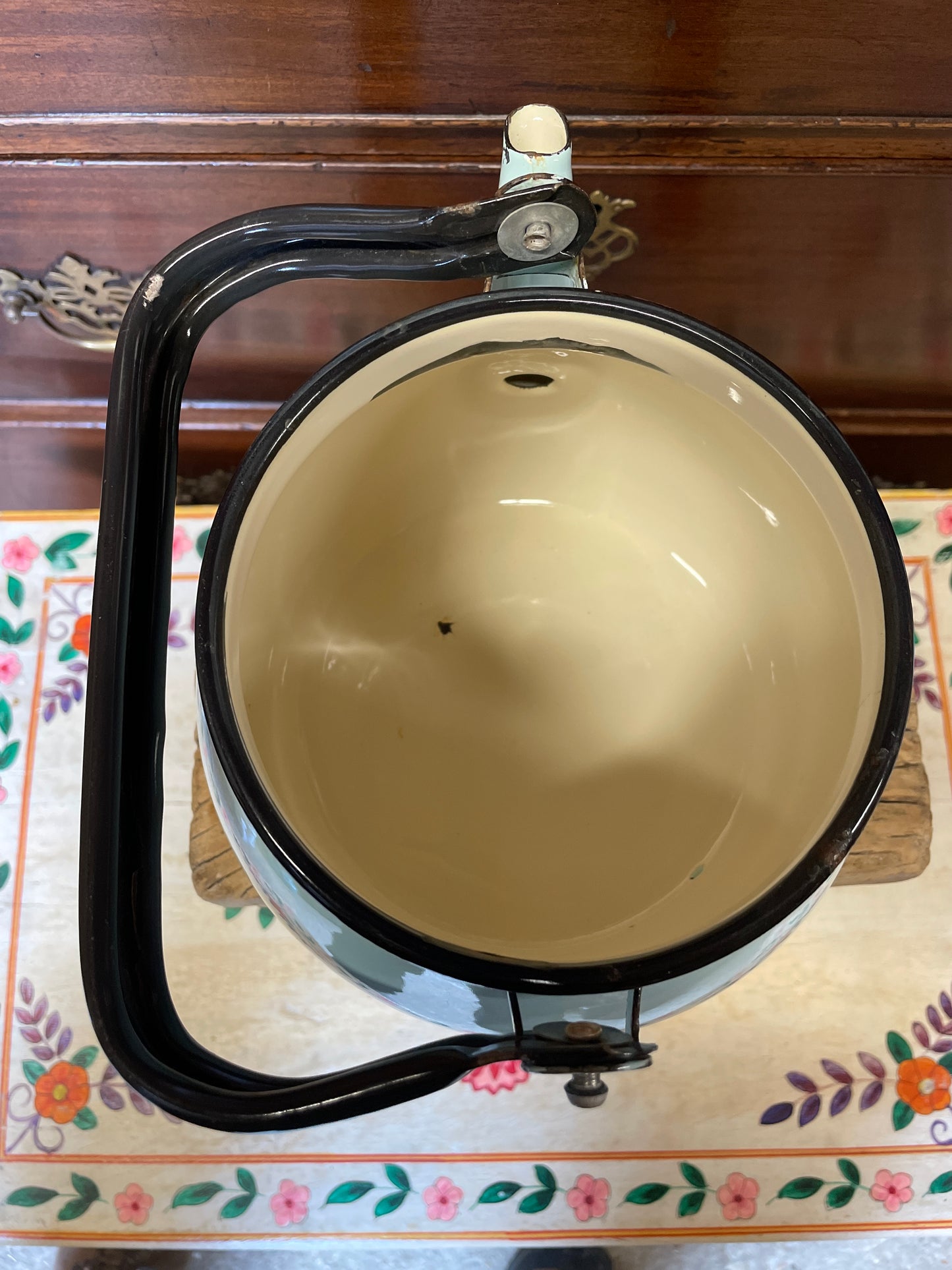 Pale blue enamel kettle with black handle and rim.